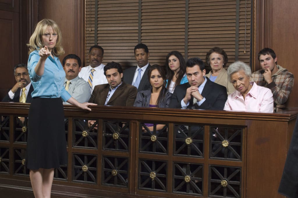 a jury along with a lawyer looking towards the cameraman in a judging manner