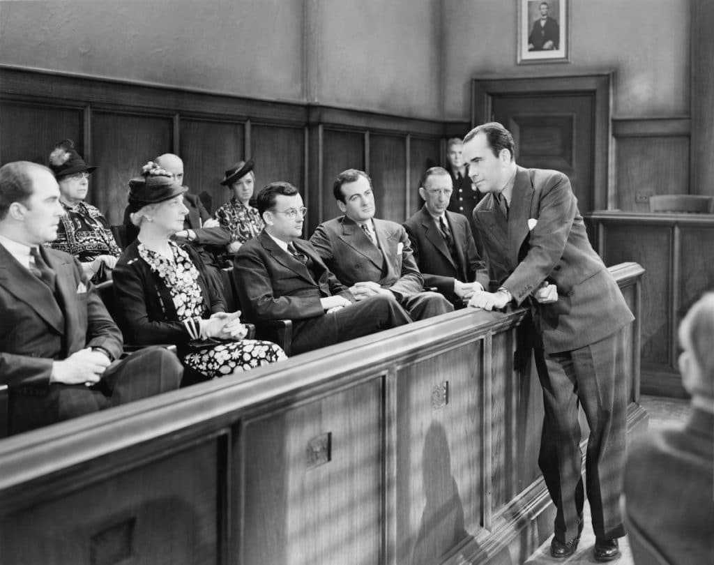 a black and white image of a jury listening to a lawyer's opening statements